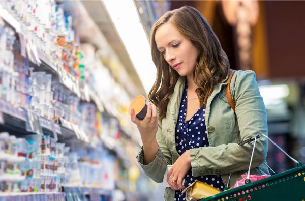 Young lady in a grocery aisle reading price of an item in her hand