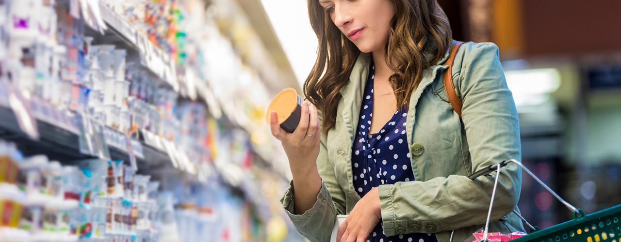 Woman shopping in grocery store comparing high grocery prices due to inflation
