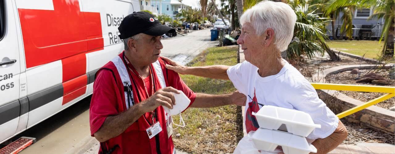 Red Cross volunteer helping old lady with food