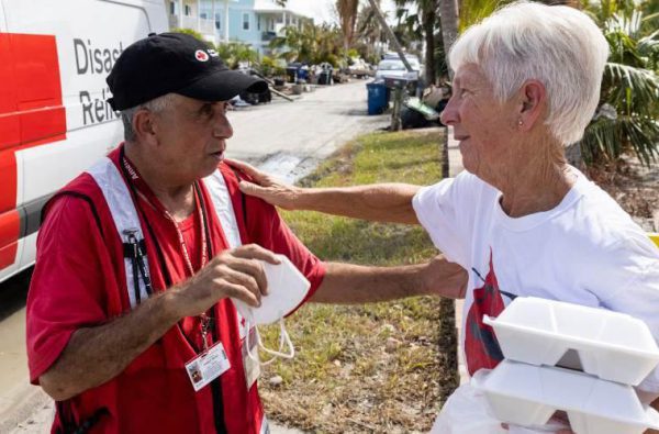 Red Cross volunteer helping old lady with food