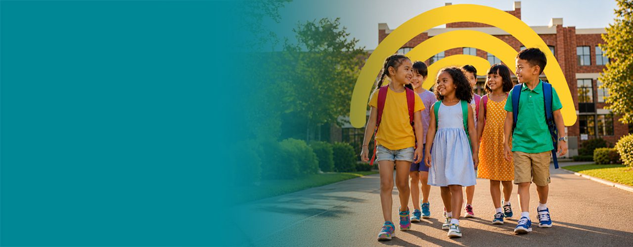Group of smiling school children walking together outside a school building,